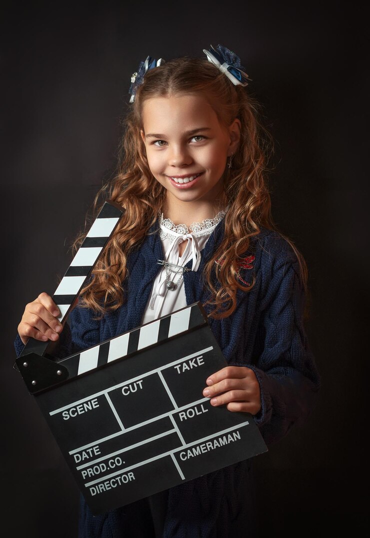 School girl with a clapperboard against dark background